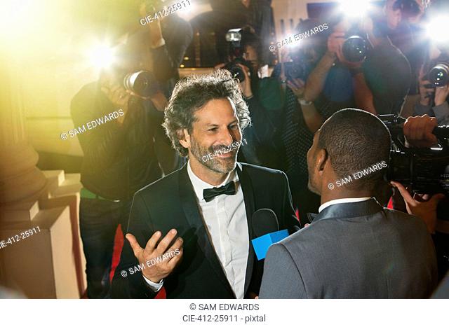 Celebrity being interviewed and photographed by paparazzi photographers at event