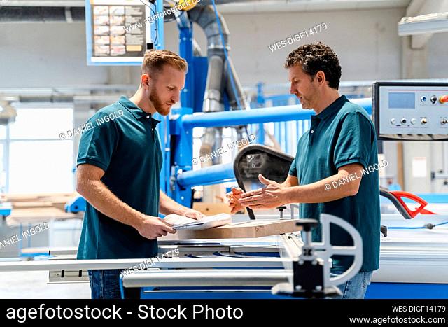 Two male carpenters working together in production hall