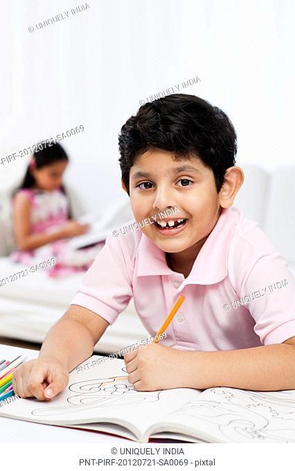 Boy making drawings with his sister in the background