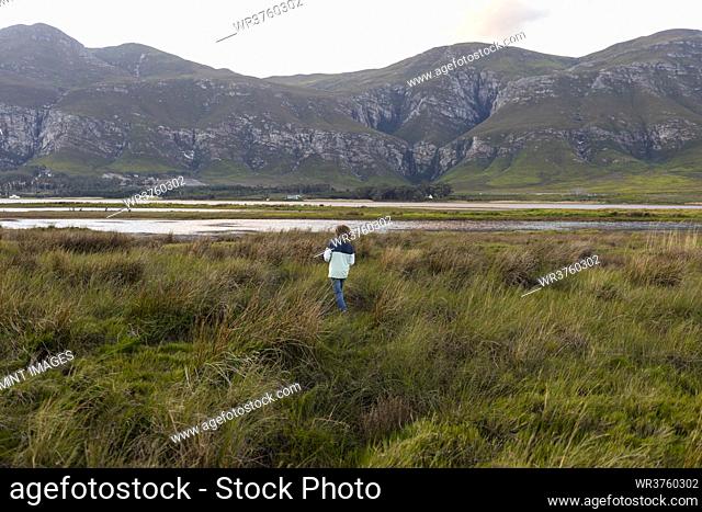 A boy exploring the shore of a lagoon in the shadow of the Kleinriver mountain range