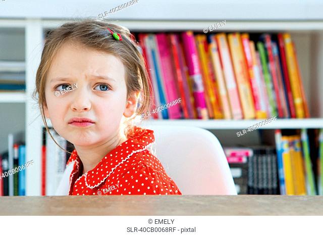 Frowning girl sitting at table
