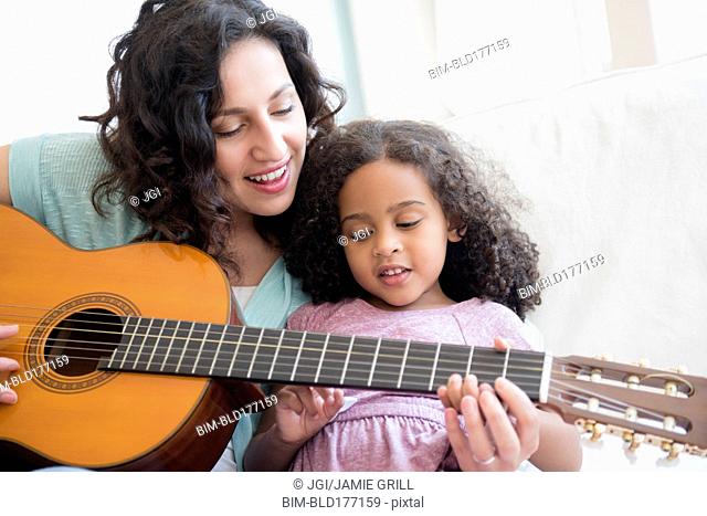 Mother teaching daughter to play guitar