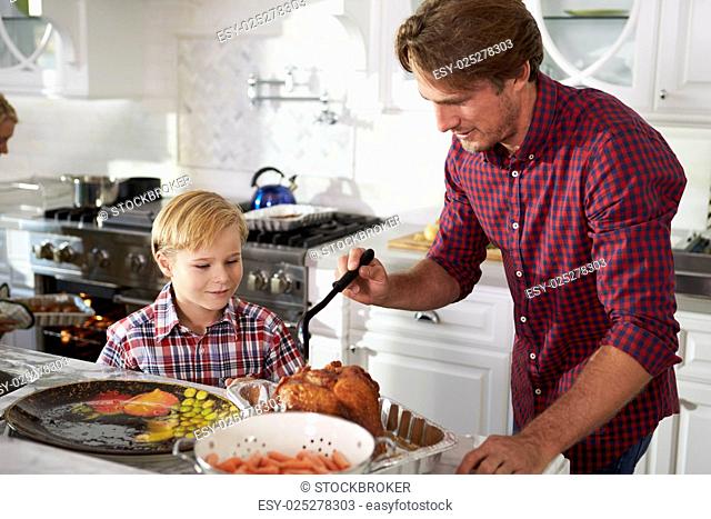 Father And Son Preparing Roast Turkey Meal In Kitchen