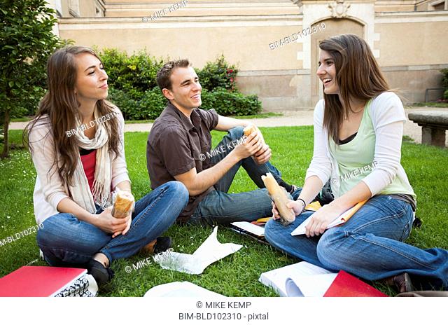 Caucasian friends eating lunch on grass
