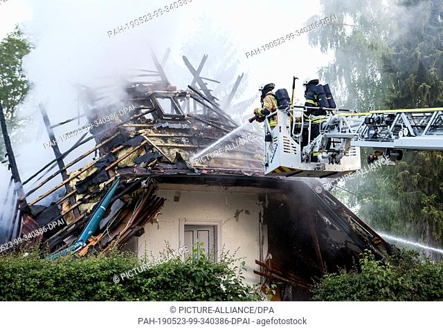 23 May 2019, Schleswig-Holstein, Wohltorf: Firefighters extinguish the smoking debris of a house that was destroyed in a fire