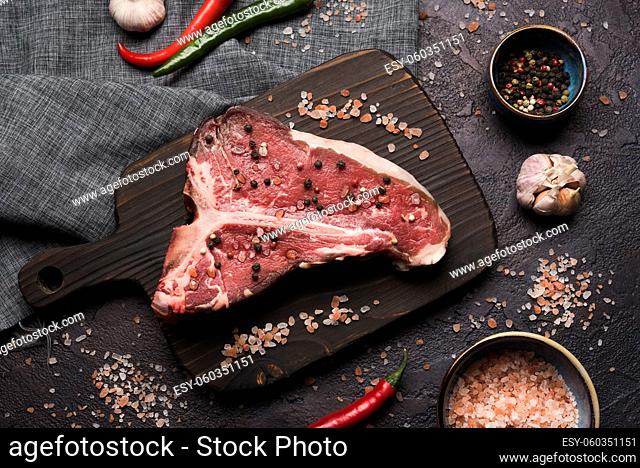 flat lay raw t bone steak with pepper salt