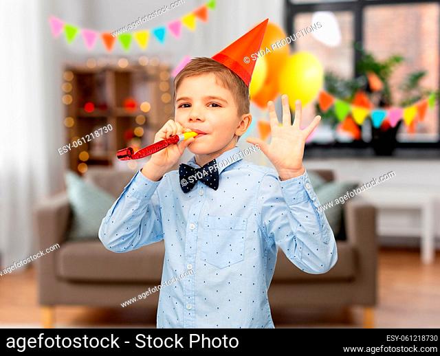 smiling boy in birthday party hat with blower