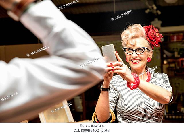 Quirky vintage woman photographing boyfriend in antiques emporium