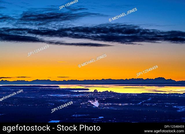 Anchorage, Alaska as seen from Arctic Valley Road while the sun sets on a winters night. The Cook Inlet and the Alaska Range are in the background; Anchorage