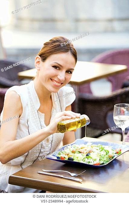 Pretty woman enjoying a salad in a restaurant outdoors smiling at camera