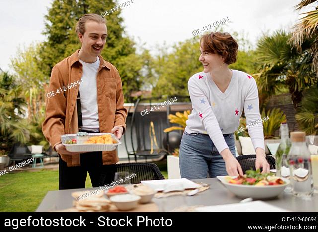 Young couple setting patio table for lunch