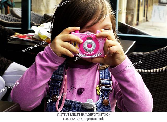 A little girl plays at being a photographer