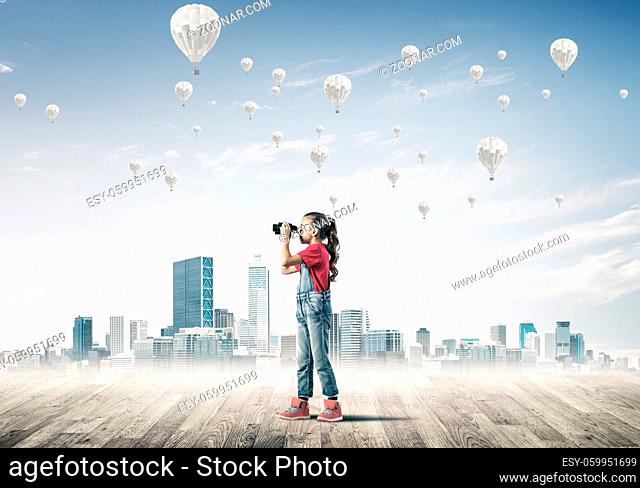 Cute kid girl standing on wooden floor and aerostats flying in air