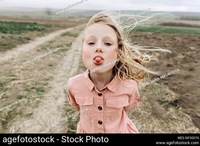 Girl sticking out tongue at agricultural field