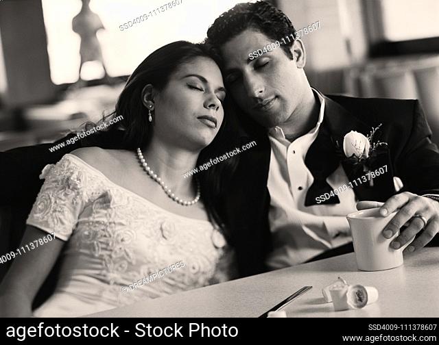 Bride and groom with eyes closed at diner