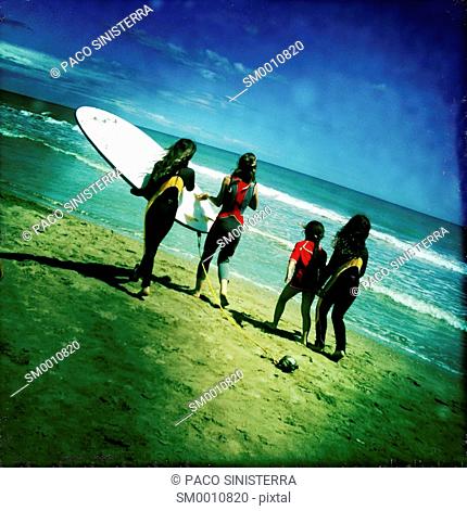 Girls playing with surfboard on the beach in Benicassim, Castellon, Valencia, Spain