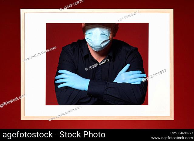 picture of a man gloves and mask arms crossed on a red background