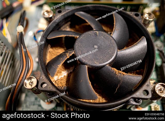 a very dirty computer fan inside a computer is cleaned by a vacuum cleaner