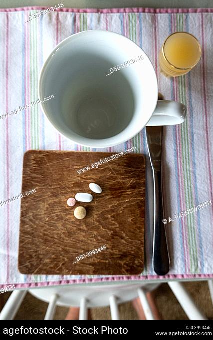 A table with an empty cup and a plate with health pills for a senior