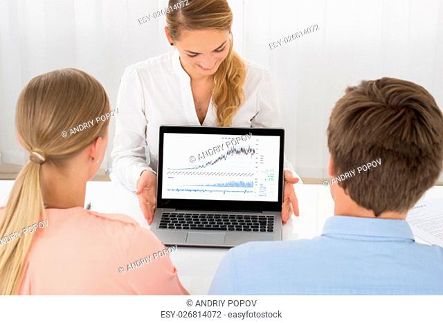 Happy Female Consultant Showing Graph To Young Couple