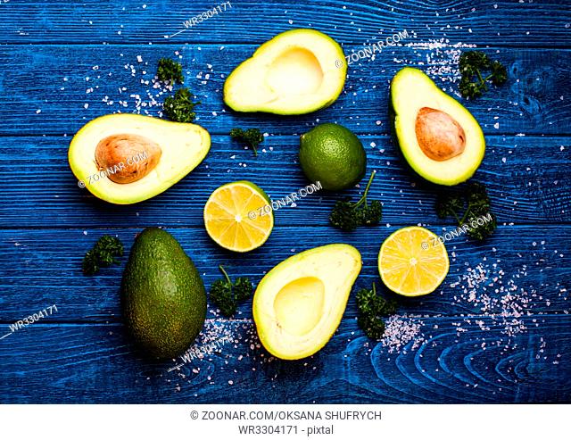 Fresh avocado, lime, parsley and salt on old blue wooden background
