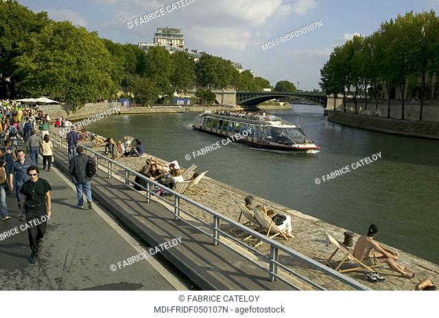 Tourists or Parisian along the quays of the Seine, walking or sitting in deckchairs