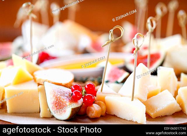Assortment of cheese on wooden board. a buffet table at a party outdoors