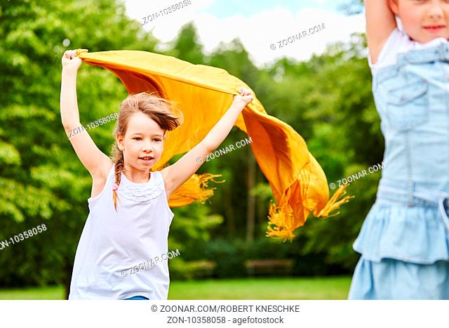 Mädchen läuft mit einem wehenden Tuch im Wind im Herbst