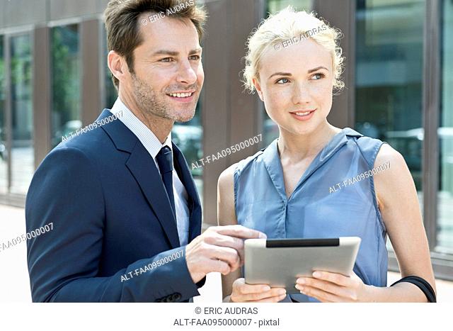 Real estate agent with digital tablet showing property to potential buyer