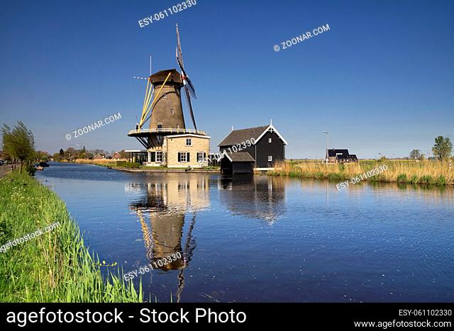 View over the river Graafstroom to the windmill De Vriendschap in the village Bleskensgraaf on a clear and crisp day in spring