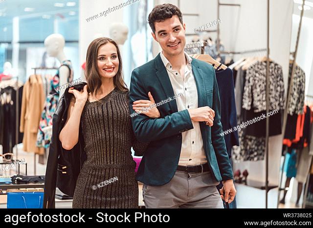 Woman and man shopping clothes in fashion store looking at the new collection