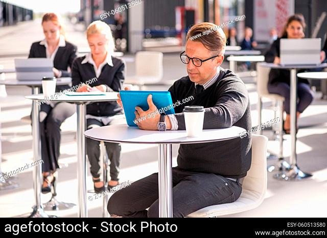 Many business people sitting in cafe , focus on man with tablet pc
