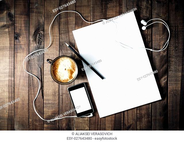Photo of blank stationery on vintage wooden table background. ID template. Mockup for branding identity. Letterhead, coffee cup, phone, pencil and headphones
