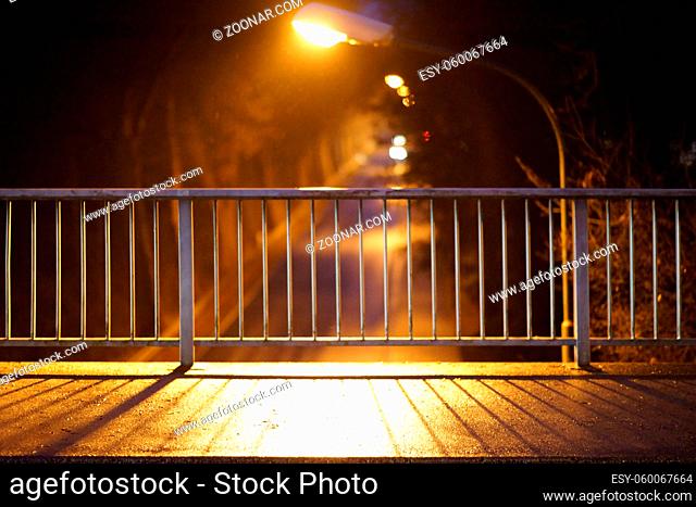 Die Nahaufnahme eines Gehweges einer Brücke am Abend dessen Geländer symmetrische Schatten werfen