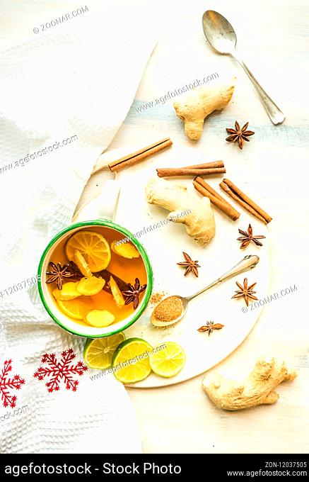 Cup of spiced tea with cinnamon sticks, anise star, lemon and jinger on rustic table