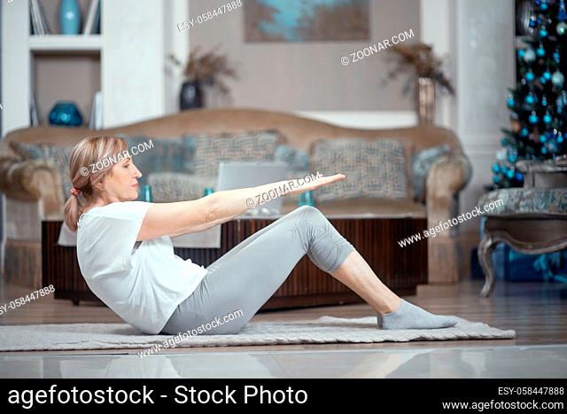 A Woman Over 50 Years Old Doing Yoga at Home. Lying on the Floor She Performs Exercises Asana. A Woman Likes Yoga