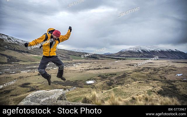 Hiker male, makes a joyful jump, Rangitata River Valley, Ashburton Lakes, Ashburton, Canterbury, New Zealand, Oceania