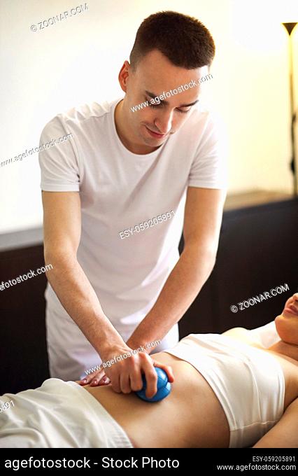 Male masseur rubbing back of customer with help of rubber vacuum cup working in salon
