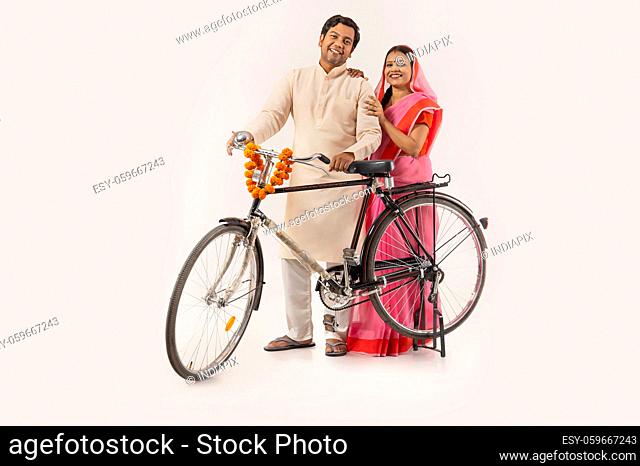 A HAPPY RURAL COUPLE STANDING TOGETHER AND POSING WITH NEW CYCLE