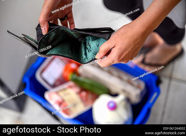 A woman ended up with an empty wallet after a basic grocery shopping before payday. She is checking her purse, but she has no cash money or credit card left in...