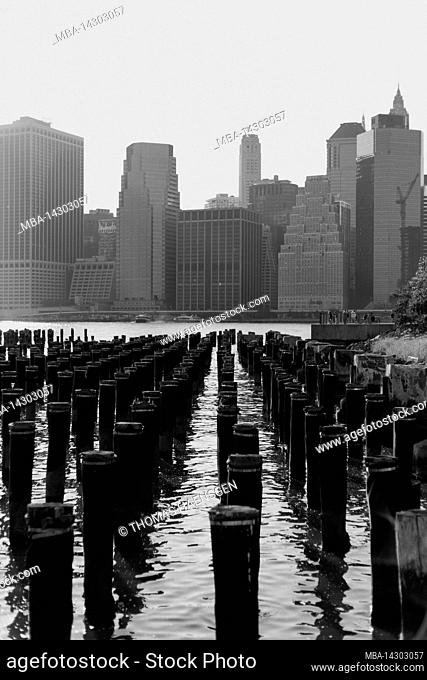 Brooklyn Heights, New York City, NY, USA, Wooden Pillars in East river seen from the old Pier 1 at Brooklyn Bridge Park. The Skyline of Lower Manhattan in the...