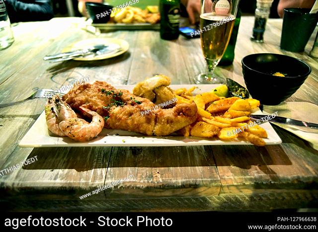 Plate in a restaurant in Walvis Bay with a piece of fresh fish fillets, shrimps and French fries, taken on 01.03.2019. While inland Namibia is mainly meat as...