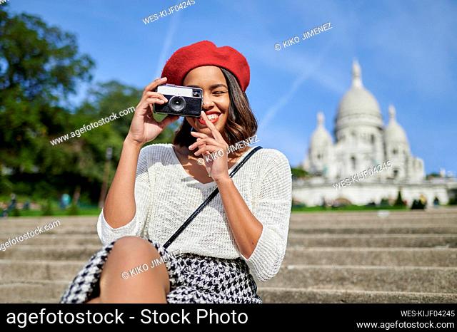 Female tourist photographing through camera at Basilique Du Sacre Coeur, Montmartre in Paris, France