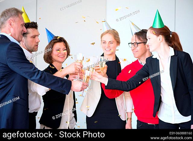 Happy business people holding flute with champagne and smiling at colleagues at party