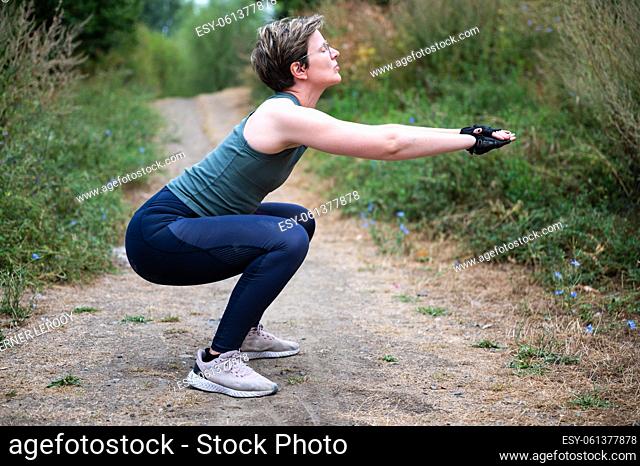 Active 36 year old white woman doing a squat outdoors, Brussels, Belgium