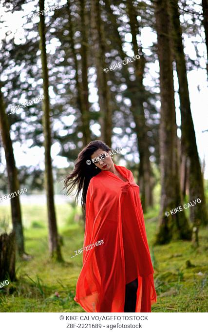 Hispanic woman with a red cloak, recreating a modern fairy tale of Little Red Riding Hood