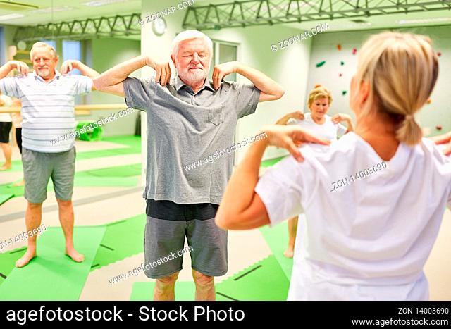 Trainer oder Physiotherapeutin zeigt Senioren eine Rückenübung in der Krankengymnastik