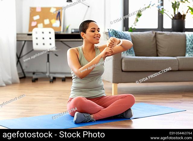 woman with smart watch and exercise mat at home