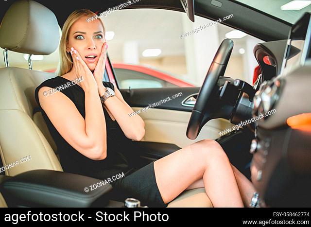 Beautiful woman on front seat of new electo car. Woman impressed by new vehicle