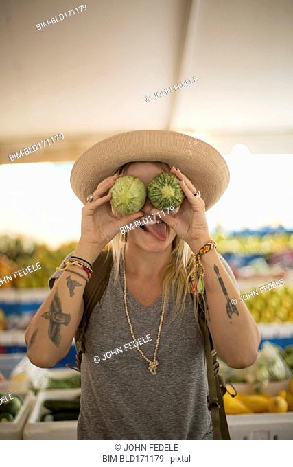 Caucasian woman making a face with fruit in farmers market